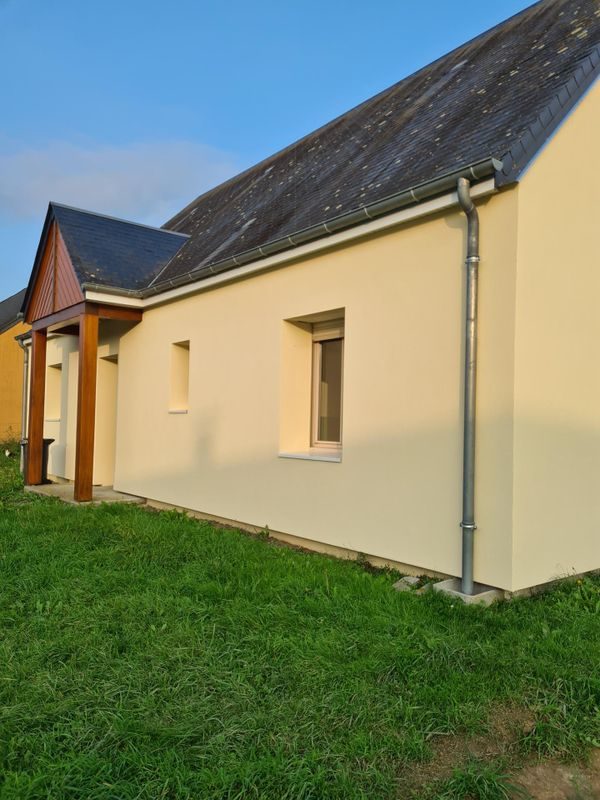 Maison de plain-pied isolée par l'extérieur, enduit crème, toit d'ardoise et porche en bois