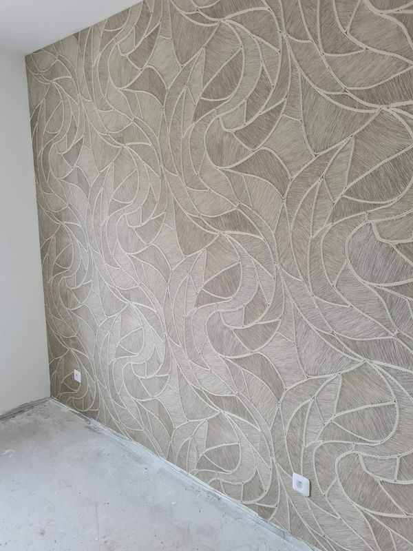 Mur couvert d'un revêtement gris à motif de feuilles, posé dans une pièce en travaux